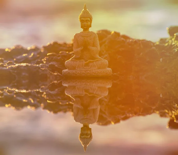 Фигура Будды, медитирующего у моря на рассвете — стоковое фото