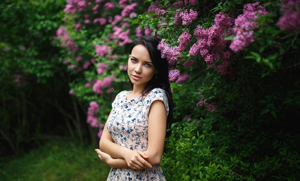 Vacker flicka stående i en rosa blommor — Stockfoto