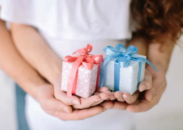 De jonge familie bezit een roze en blauwe cadeau-verrassing in de hand. — Stockfoto