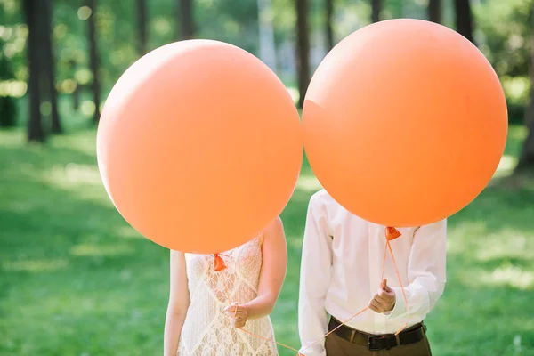 Sposi con palloncini arancioni. la fotografia divertente con persone appena sposate . — Foto Stock