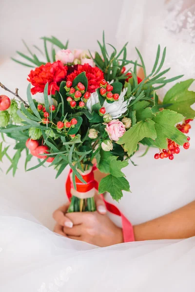 Mooie vrouw in een witte trouwjurk een boeket bloemen in de hand te houden. Bruiloft bruids boeket op een witte achtergrond. — Stockfoto