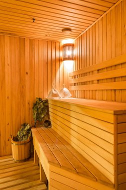 Interior of a sauna. Advantage for health. Oak brooms for a steam room in traditional russian wooden bath. clipart