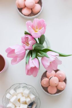 Bahar arka plan. Pembe Macarons, Lump & şeker, bir fincan çay ve bir buket Pembe Lale beyaz bir tablo görünümü top. Taze Lale buketi ile natürmort. Tepsi dekore edilmiş.