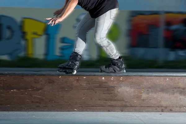 Fiatal férfi görkorcsolya. Rollerblader közelében graffiti. Nem félnek a sebesség. Lábak személy a görkorcsolya közelről. vezetési koncepció, a görgők a színpadon. — Stock Fotó