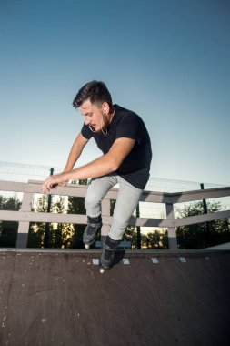 Şık adam paten ve müzik kulaklık açık havada. Patenci rampa üzerinde. Yüksek hızlı ve tehlikeli püf noktaları.