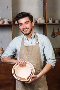 pişmiş toprak el yapımı bir dizi gösterilen yakışıklı gülümseyen İspanyol potter. Potters atölye.