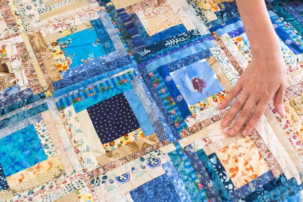 A kaukázusi női kéz érintése egy színes patchwork takaró kék geometriai mintázattal. Színes szedett-vedett takaró része. Kézzel készített. — Stock Fotó