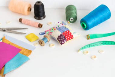 Dikiş araçları kumaş, makas, iğneler, makaralar farklı renk iplik, teyp, düğme metni için boş bir alan ile beyaz bir arka plan üzerinde ölçmek. Dikiş araçları moda tasarım.