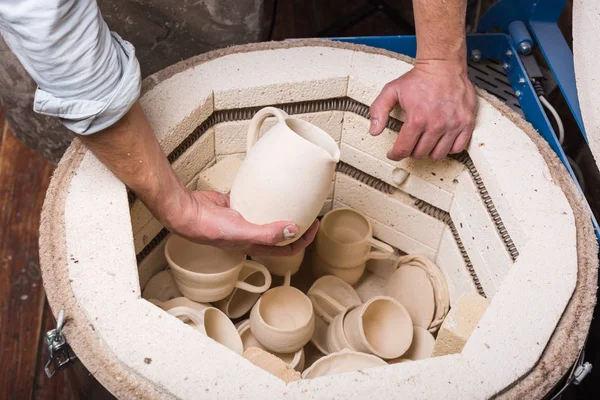 Roasted ceramic products without glaze in the potters hands close up. Top view. Art and business, hobby and freelance working concept. Pottery making kiln ready for the firing process. — Stock Photo, Image