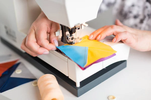 Női kezek firkákat a varrógép geometriai színes szövet darab patchwork takaró. a tervezők kezét a a varrógép közelről. — Stock Fotó