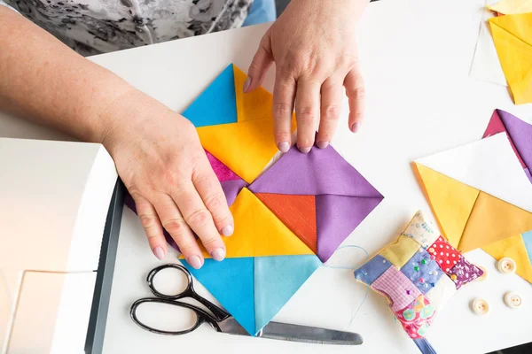 Mains féminines tenant des pièces de tissu colorées géométriques pour patchwork quilt. créateur de mode crée une nouvelle collection de vêtements. vue de dessus . — Photo