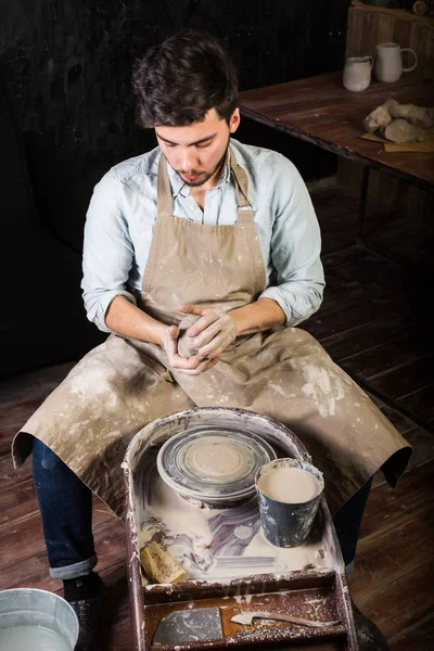 Le beau jeune potier espagnol créant le produit de l'argile sur une roue torsadée de potiers. roue de potiers avec la pièce . — Photo