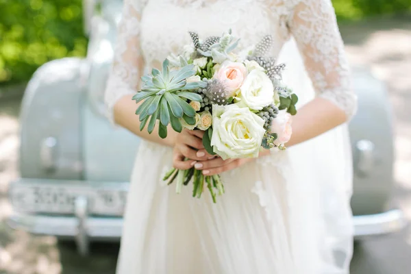 Mulher bonita em um vestido de noiva branco segurando um buquê de flores de rosa na mão em um fundo de carro retro fora. Buquê de casamento nupcial em um fundo branco . — Fotografia de Stock