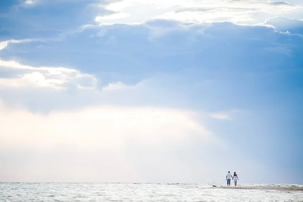 Mujer feliz y el hombre en luna de miel en la hermosa luz del sol en el fondo de la playa. Pareja romántica cogida de la mano contra el mar. Espacio vacío para el texto . — Foto de Stock