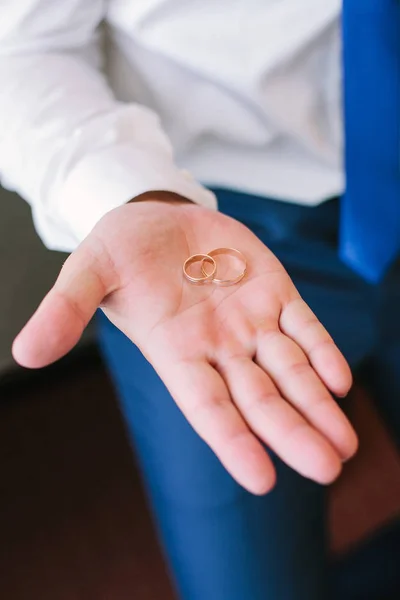 Anillos de bodas de oro en la palma de los novios en una camisa blanca, de cerca . — Foto de Stock