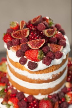 Gri arka plan üzerinde çıplak kek. Taze meyveleri ve beyaz krema ile pasta yakın çekim.