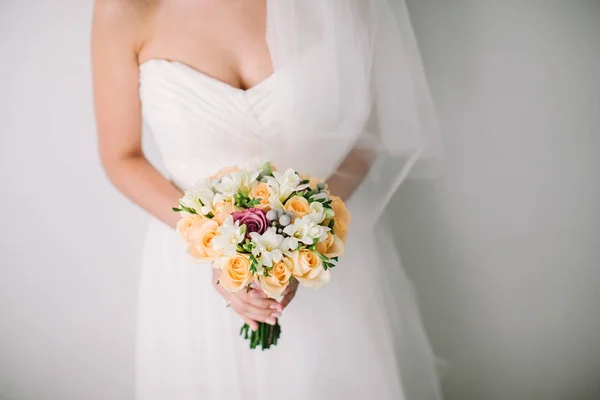 Hermosa mujer en un vestido de novia blanco sosteniendo un ramo de flores de rosa en la mano fuera. Ramo de novia de boda sobre un fondo blanco . — Foto de Stock