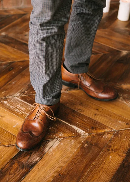 Bacaklar mans damalı pantolon ve kahverengi çizmeleri loafer'lar bir ahşap zemin üzerinde kapat. Düğün hazırlıkları için. — Stok fotoğraf