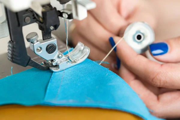 Naaien en quilten in de werkplaats van een kleermaker - close-up op de handen van een kleermaker invoegen een klosje draad voor naaimachine — Stockfoto