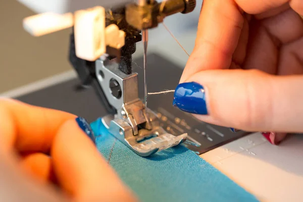 Handarbete och hand quiltning i verkstaden för en skräddare - närbild på fingrarna med en manikyr sticka tråden i nålen på symaskinen — Stockfoto