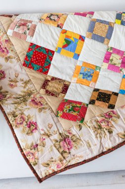 Renk patchwork yorgan kanepe beyaz bir arka plan olarak yatan vintage çiçek desenli bir parçası. Renkli bölük pörçük battaniye. El yapımı. Metin için boş spase.