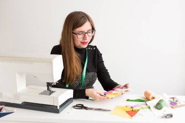 iğne işi ve el kapitone genç bir kadın, beyaz arka planda - terzi atölyesinde genç gülümseyen kadın terzi dikiş makinesi üzerinde dikili ellerini renkli kumaş parçalarını tutar