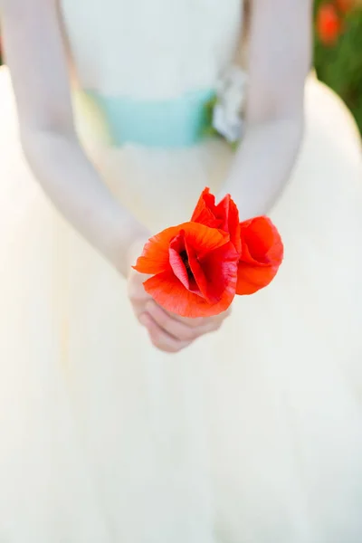 Vallmo, jordbrukssektorn, produktion och ekologi, natur och sommaren koncept - närbild på röd vallmo knoppar i två händer av en liten flicka klädd i vit bröllop kläder på ett fält av vallmo, vertikal — Stockfoto