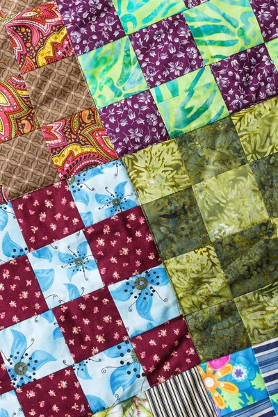 Part of symmetric geometry pattern color patchwork quilt as background. Colorful Scrappy blanket with pattern of small squares. Handmade.