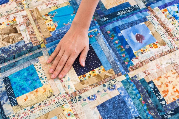 La main féminine caucasienne touchant une patchwork de couleur avec motif géométrique bleu. Une partie de la couverture Scrappy colorée. Fait à la main . — Photo