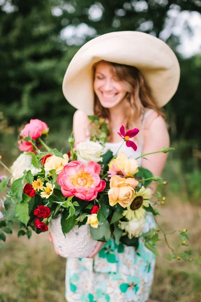 Buquê, pessoas, férias de flores, dom e conceito de arranjo floral close-up em belo buquê fresco, sorrindo jovem mulher em vaso chapéu fantasia segurando com flores de verão no fundo da natureza . — Fotografia de Stock