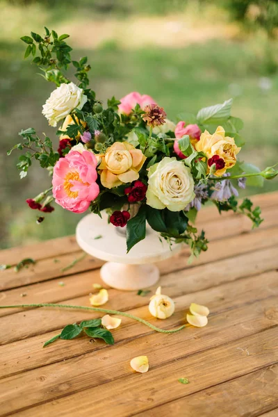 Csokor, virág ünnepek, ajándékok és virág elrendezése koncepció - közeli, a csokor, az aranyos sárga és Fehér Rózsa, rózsaszín bájos küldönc, a szegfű, a hajtások a wild rose, fehér váza, a fából készült asztal. — Stock Fotó