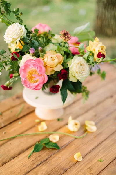 Boeket, bloemen, geschenken en floral regeling concept - top u bekijken over vers boeket van gele en witte rozen, rode anjers, roze charmante peon, scheuten van de wilde roos, in witte vaas op houten tafel. — Stockfoto