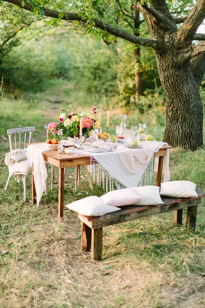 piknik, gıda, yaz, tatil kavramı - festively dekore edilmiş ahşap piknik masa ağaçlar, buket, limonata, gözlük, meyve tabakları, şamdanlar, yastık ve battaniye sandalyeler ve tezgah üzerinde sürahi arasında