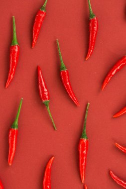 Red hot chili peppers, popüler baharatlar kavramı - güzel kırmızıya yakın çekim sıcak biber kırmızı arka plan, yeşil kuyrukları, kolaj üzerinde serbestçe izole biber, yalan görünümü, düz yatıyordu top.
