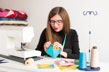 dikiş ve kapitone genç bir kadın, beyaz arka planda - güzel kadın terzi el ile renkli kumaş parçaları dikiş iğne ile bir terzi atölyesinde