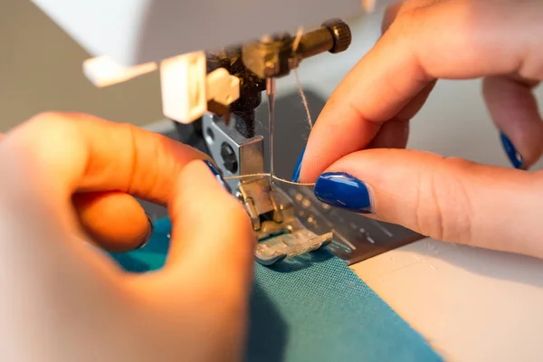 Handarbete och hand quiltning i verkstaden för en skräddare - närbild på fingrarna av skräddarsy kvinna med blå manikyr stick tråd needle symaskin — Stockfoto