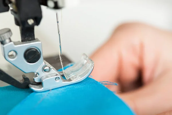 Naaien en quilten in de werkplaats van een kleermaker - close-up op de naald van naaimachine steken de stukjes gekleurde blauwe stof. — Stockfoto
