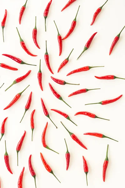 red hot chili peppers, popular spices concept - decorative pattern of red hot chili with green tails on white background, beautiful hot collage of freely lying peppers, top view, flat lay.