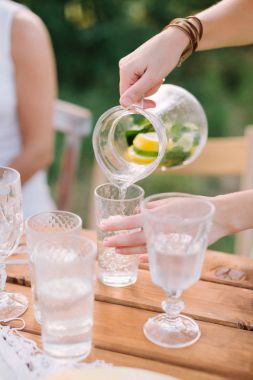 piknik, insanlar, yaz, tatil kavramı - eller, limonata sürahi gelen bir cam kabı dökülen bir sürahi dilim limon, limon, nane yaprakları, su, dekore edilmiş tablo, seçici odak kadın.