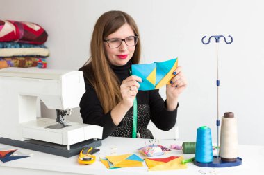 dikiş ve kapitone genç bir terzi - atölye bir resepsiyon ve yalan konu, kumaşlar, iğneleri, iğne yanındaki iki flep kumaş dikkate alınarak dikiş makinesi arkasında gözlüklü genç terzi