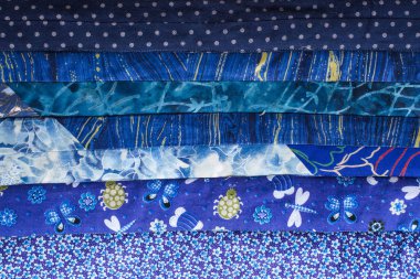 Elişi, patchwork, dikiş, ev atmosfer kavramı - Tekstil arka plan işte yoğun mavi tonları çeşitli soyut baskı ile düzeltme ekleri dikilmektedir yatay şeritler ile güzel bir yorgan