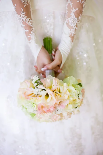 Hermosa mujer en un vestido de novia blanco sosteniendo un ramo de flores de rosa en la mano fuera. Ramo de novia de boda sobre un fondo blanco . — Foto de Stock