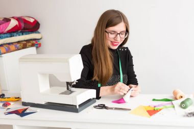 dikiş ve kapitone genç bir kadın, beyaz arka planda - genç bir kız, bir terzi, yüzünde bir gülümseme ile bir terzi atölyesinde eller tasarımcı kumaş parçaları dikiş