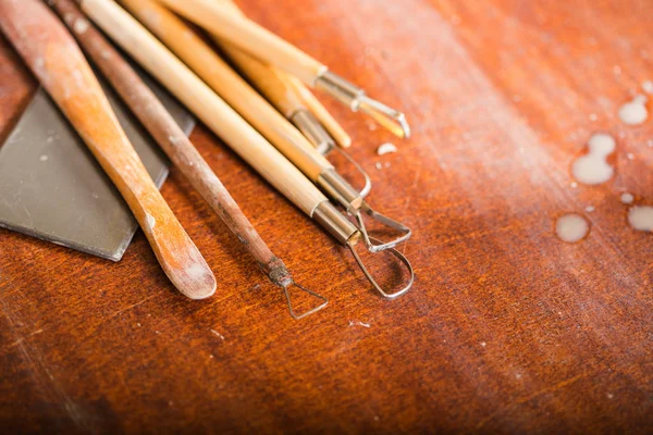 Ceramica, laboratorio, concetto di arte ceramica - primo piano su strumenti di scultura disposti su tavolo di legno, pile di argilla, profili diversi, taglierine per forme intagliate, vista dall'alto . — Foto Stock