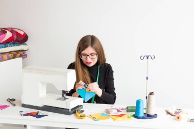 dikiş ve kapitone genç bir kadın - atölye yalan konu, kumaşlar, iğneleri, iğne yanındaki renkli doku el flep ile bir terzi kadın Danışma ve dikiş makinesi, dikiş.