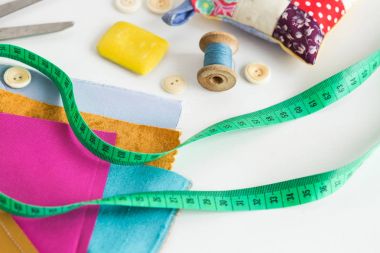 sabun dikiş, patchwork, terzilik ve moda kavramı - beyaz masa, iş parçacığı biriktirme, düğmeler, metre, iğnelik, makas, renkli patchwork kumaş parçaları, bir moda tasarımcısı araçları yakın çekim.