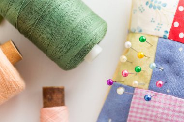 dikiş, dikiş ve kavram - renkli sevimli dikişli iğnelik ile güzel iğne, Araçlar closeup beyaz Danışma, yeşil, pembe ve şeftali iplik makaralar, düz lay, dikiş kapitone, görünümü top.