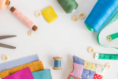 patchwork, dikiş araçları, terzilik ve moda kavramı - iplik, ölçme metre, düğmeler, makas, iğne yastığı, iğne işi için donatım renkli skeins ile beyaz masa üzerinde yakın çekim.