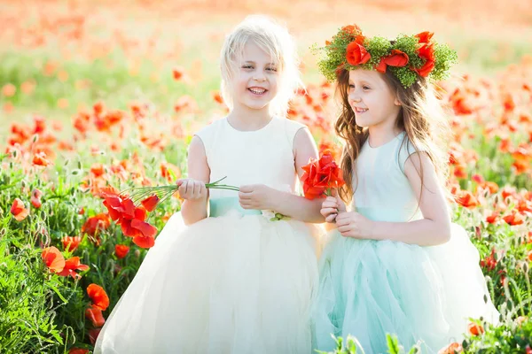 Libertad, celebración, sueño, concepto de infancia feliz - en el campo de la amapola dos novias riéndose en vestidos sin mangas blancos y azules sosteniendo posies de flores silvestres —  Fotos de Stock