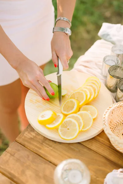 Cibo, salute, stile di vita, vegetarianismo, cucina, concetto di natura mani delle donne con manicure arancione brillante, braccialetto d'argento e orologio da polso fetta di limone e lime su piatto bianco — Foto Stock